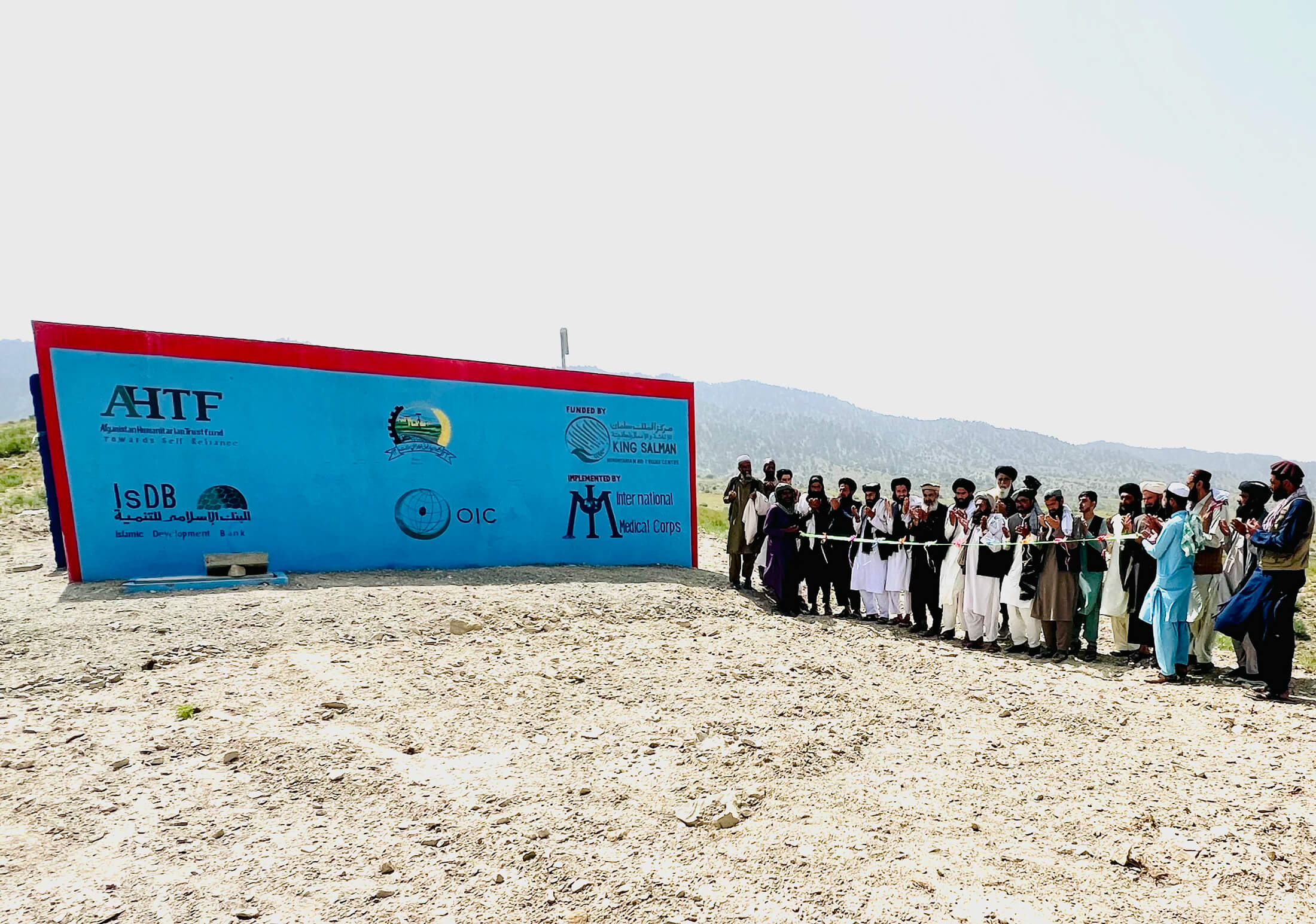 AFGH_Picture---19 Staff members and villagers cut the ribbon at an International Medical Corps-constructed water tank.
