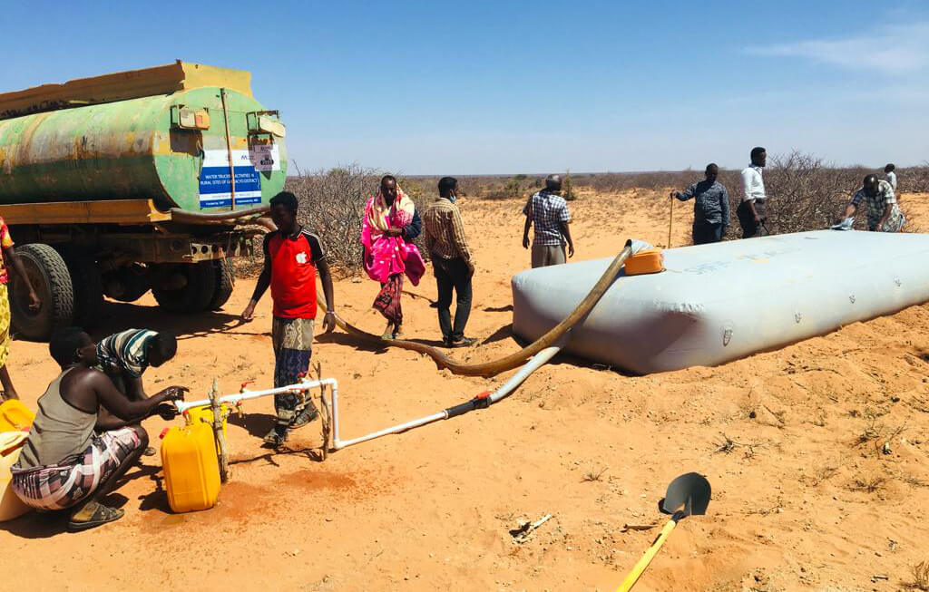 Residents of Qarsooni village located outside Galkayo, Somalia, draw water from a bladder filled with water we trucked into the area. (Photo by Adan Sheikhnur Omar.)