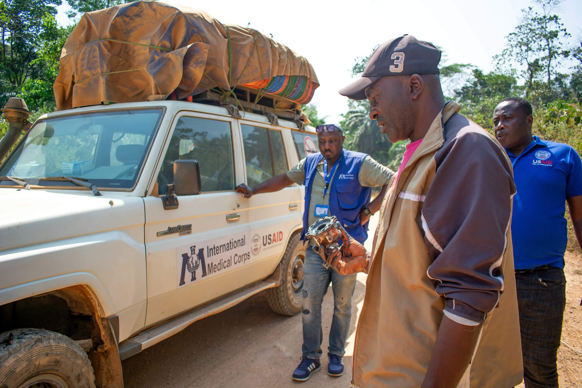 CAM_V1 Vincent Ndi holds a wheel center cap as he examines the tire of the vehicle he drives for International Medical Corps.