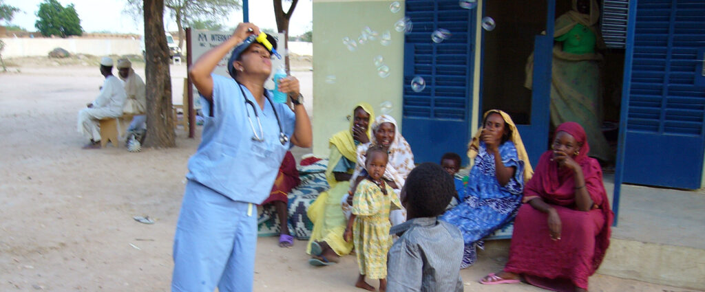 Dr. Jill John-Kall plays with children while working with International Medical Corps in Chad in 2005.