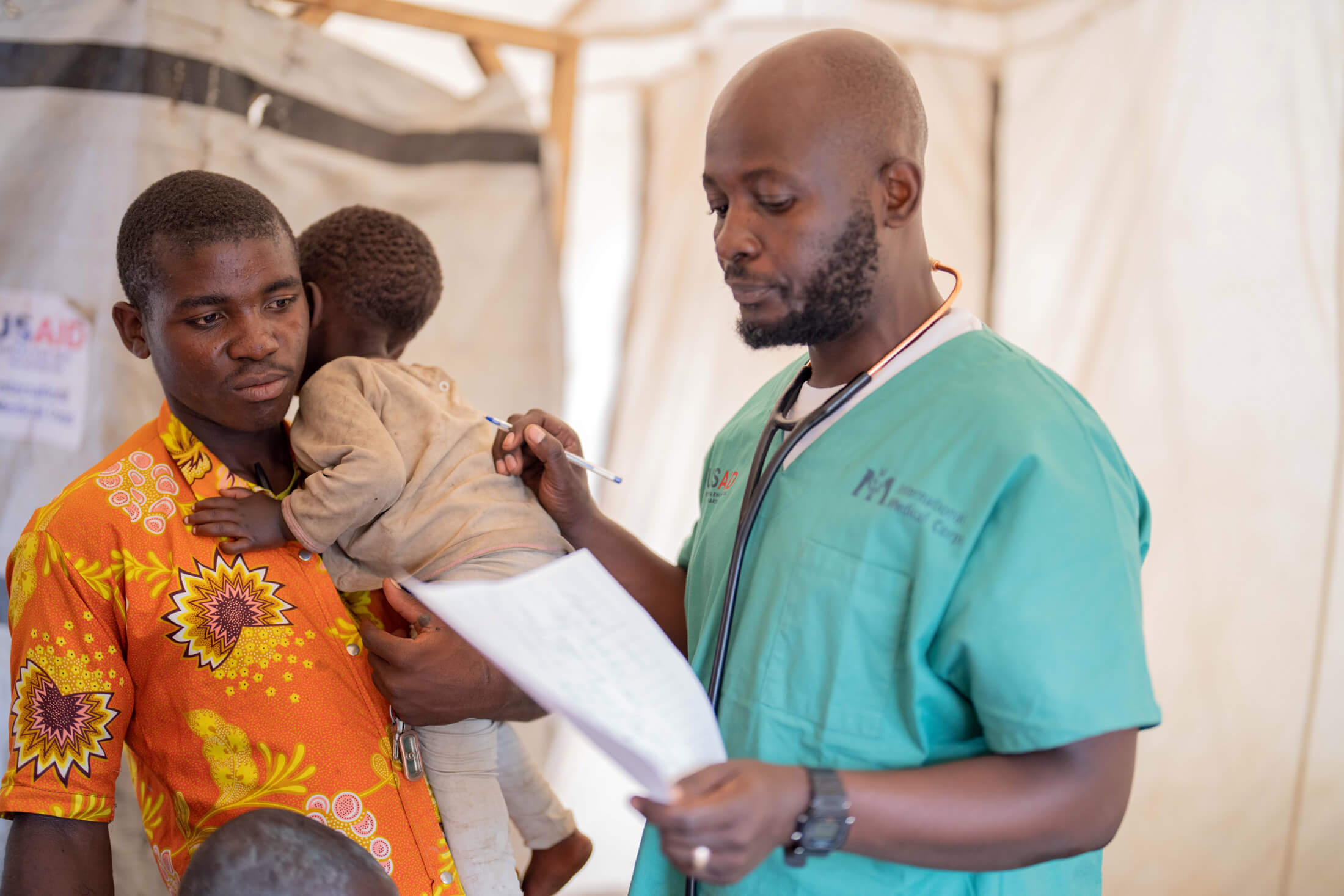 Uzima, a 29-year-old father who fled his home with his sons and lives at the Matendo IDP site, receives medication and care from Bienvenu in the MMU.