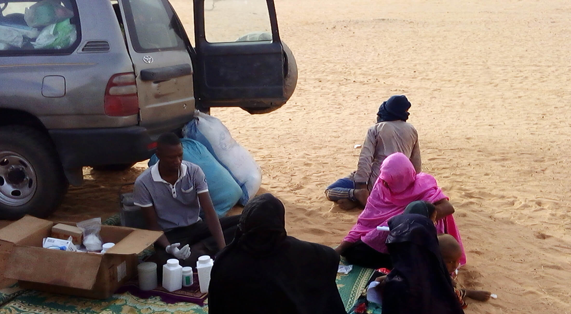 MALI_Dispensations-of-drugs-by-the-nurse-after-the-medical-consultation In Mali’s Taoudénit region, an International Medical Corps nurse dispenses medication under the shade of an MMU to patients who have just completed a medical consultation.