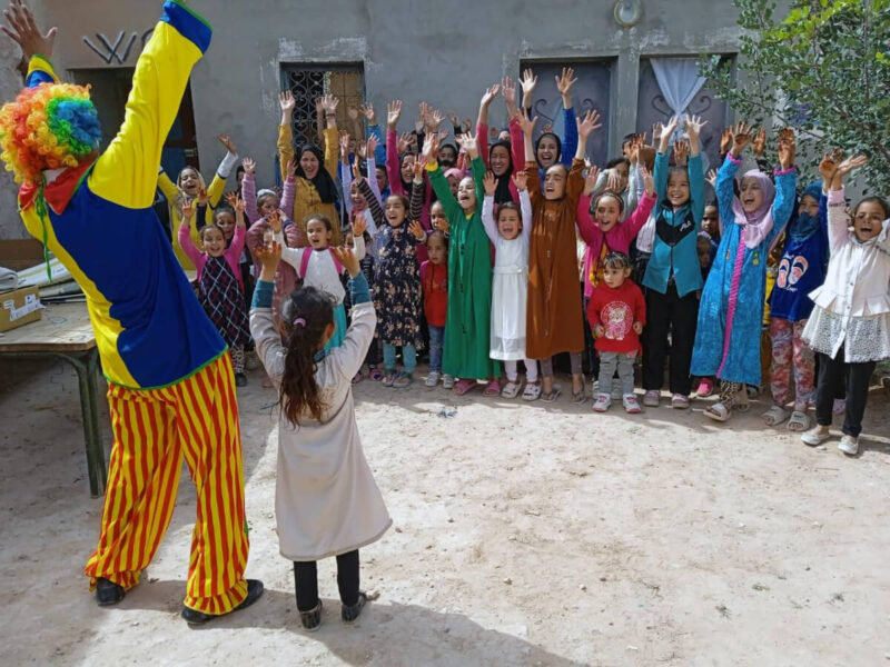 Children play with a clown during a group activity at a child-friendly space in Morocco.
