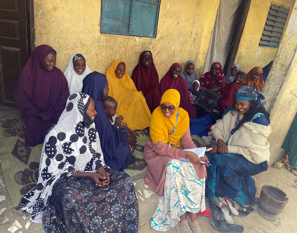 NIGERIA_Photo-6 Somalia GBV Coordinator Hiba Hassan Ahmed (front row, center) and Nigeria GBV Manager Tsumda Wakili (front, right) talk with a village savings and loan group in Bolori, Maiduguri, Nigeria.
