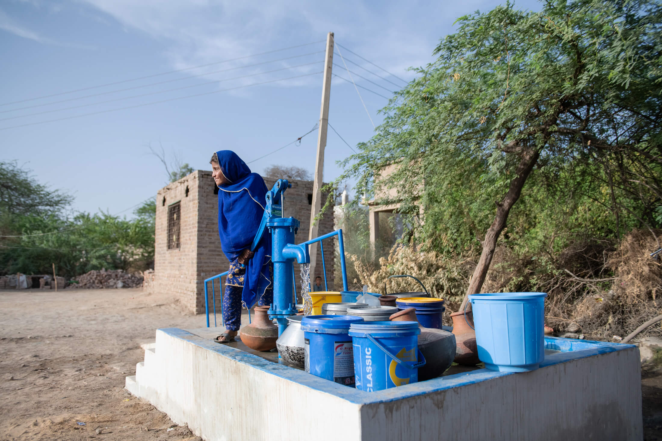 Asma pumps water for her family at a hand pump installed by International Medical Corps.