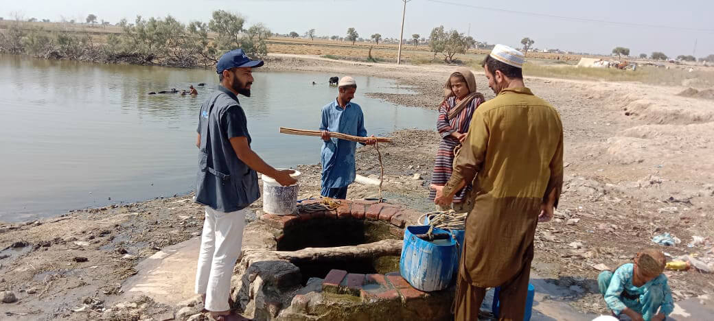 PAK_;ldkfsdl;kfg Community Mobilizer Arshad Ali Sodhro helps flood-affected villagers learn how to use water purification tablets.