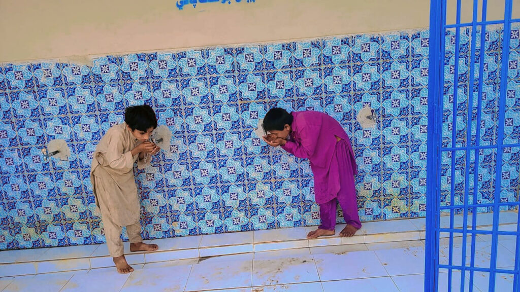 Children drink from the taps at the water collection area that was rehabilitated by International Medical Corps.