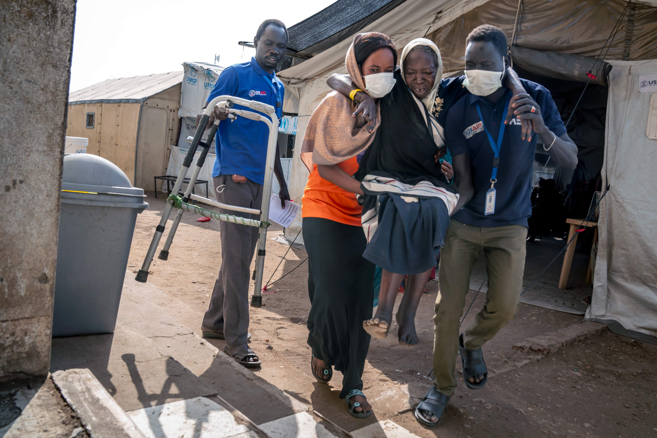 SOUTH-SUDAN_DZA_IMC-Renk_2024_03_14-DZA08407-Enhanced-NR Staff members carry a disabled woman to our clinic.