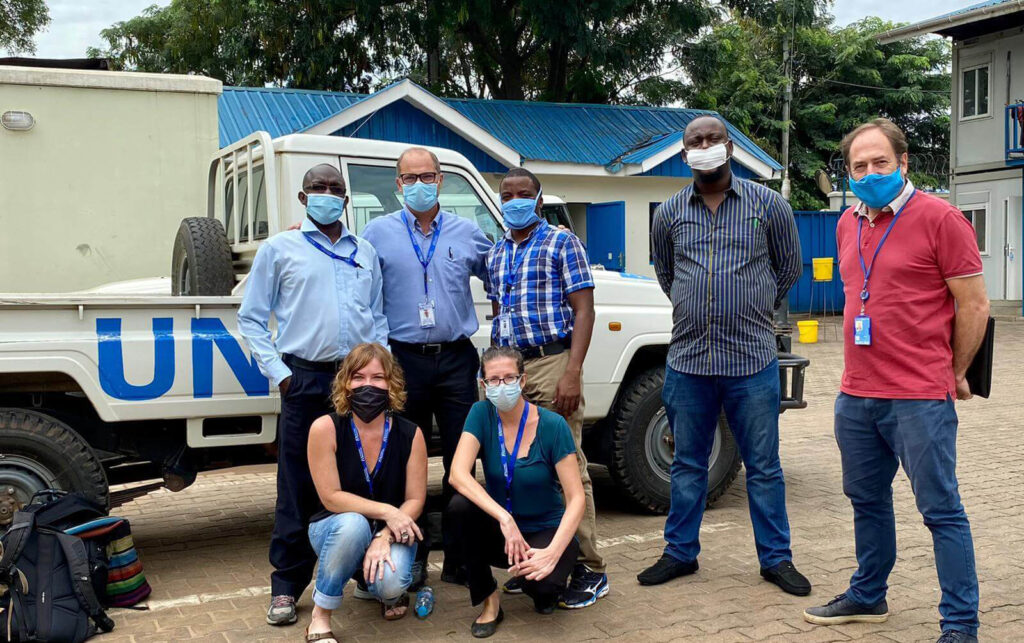 The EMT sent five critical-care specialists to the IDU. Pictured in back row, left to right: Henry Kiwumulo (Biomedical Engineer), Dr. Gordon Johnson (ICU Physician), Dr. Joseph Niyitegeka (Anesthesiologist and Critical Care Specialist), Dr. Edmund Nabena (former Emergency Health Specialist) and John Henry Gray (former World Health Organization Incident Manager for COVID-19 in South Sudan). Pictured in front row, left to right: Audrey Landmann (former Emergency Medical Team Lead) and Laura Fisher (ICU Nurse).