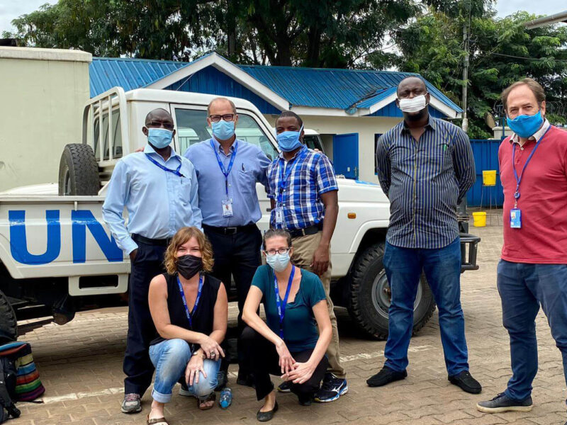 The EMT sent five critical-care specialists to the IDU. Pictured in back row, left to right: Henry Kiwumulo (Biomedical Engineer), Dr. Gordon Johnson (ICU Physician), Dr. Joseph Niyitegeka (Anesthesiologist and Critical Care Specialist), Dr. Edmund Nabena (former Emergency Health Specialist) and John Henry Gray (former World Health Organization Incident Manager for COVID-19 in South Sudan). Pictured in front row, left to right: Audrey Landmann (former Emergency Medical Team Lead) and Laura Fisher (ICU Nurse).