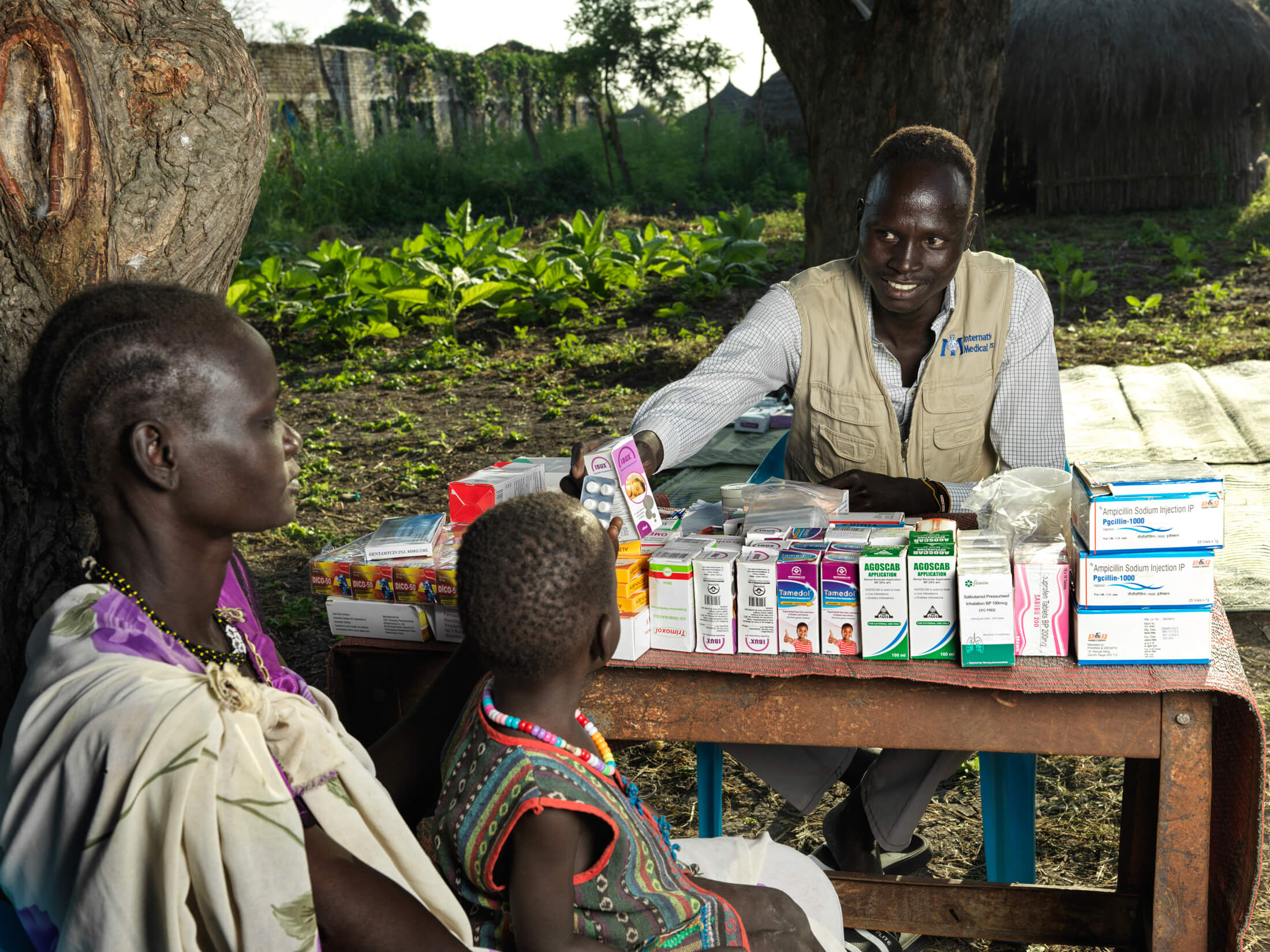 SSUDAN_IMC_SSD24__0942 International Medical Corps Pharmacy Assistant Santo Paulino distributes medicines to a mother and her child in Dolieb.