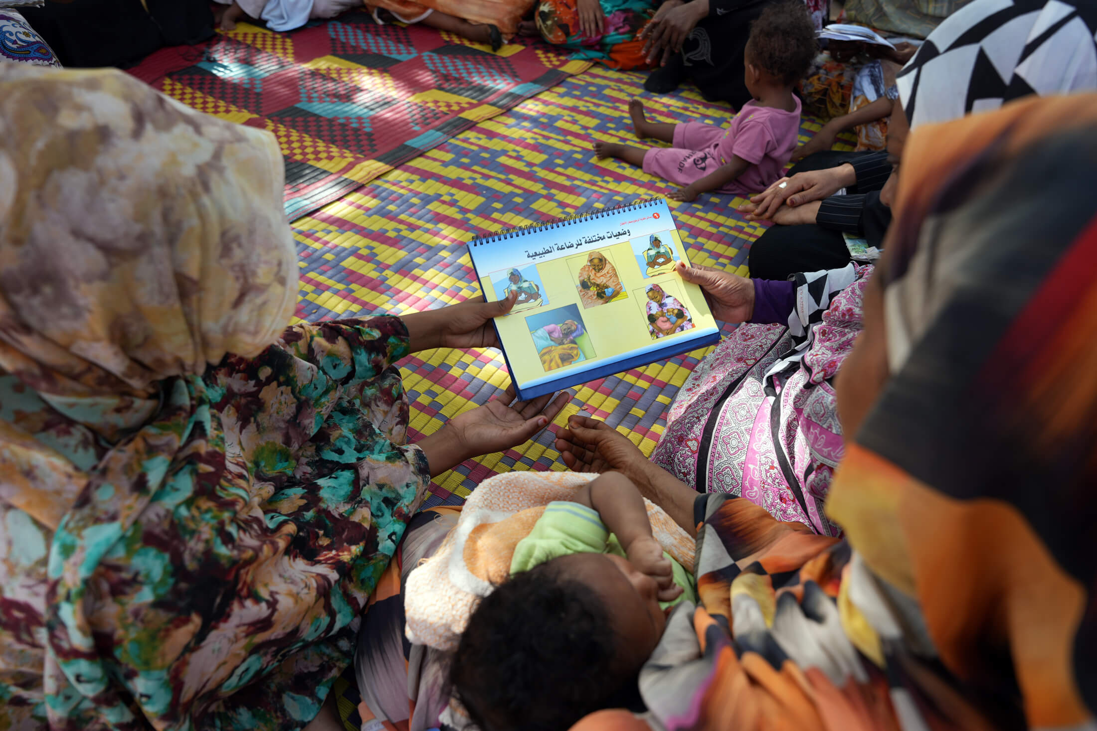 SUD_DSC05246 Mothers learn about comfortable breastfeeding positions from an instructional book.