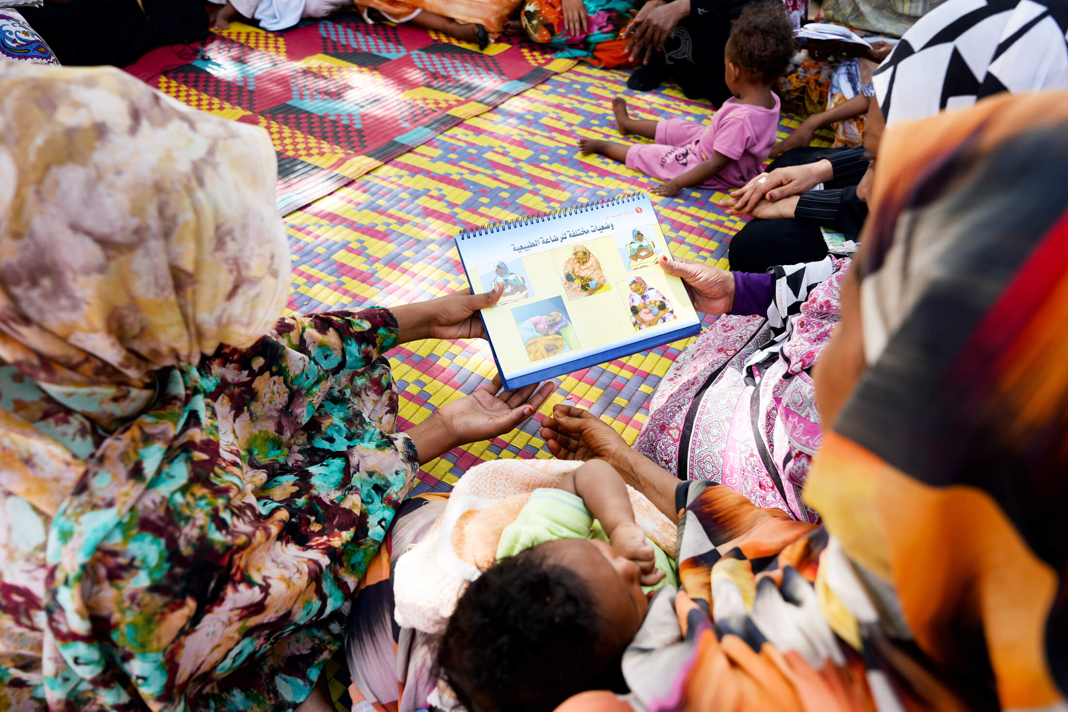 SUD_DSC05246 Mothers learn about comfortable breastfeeding positions from an instructional book.