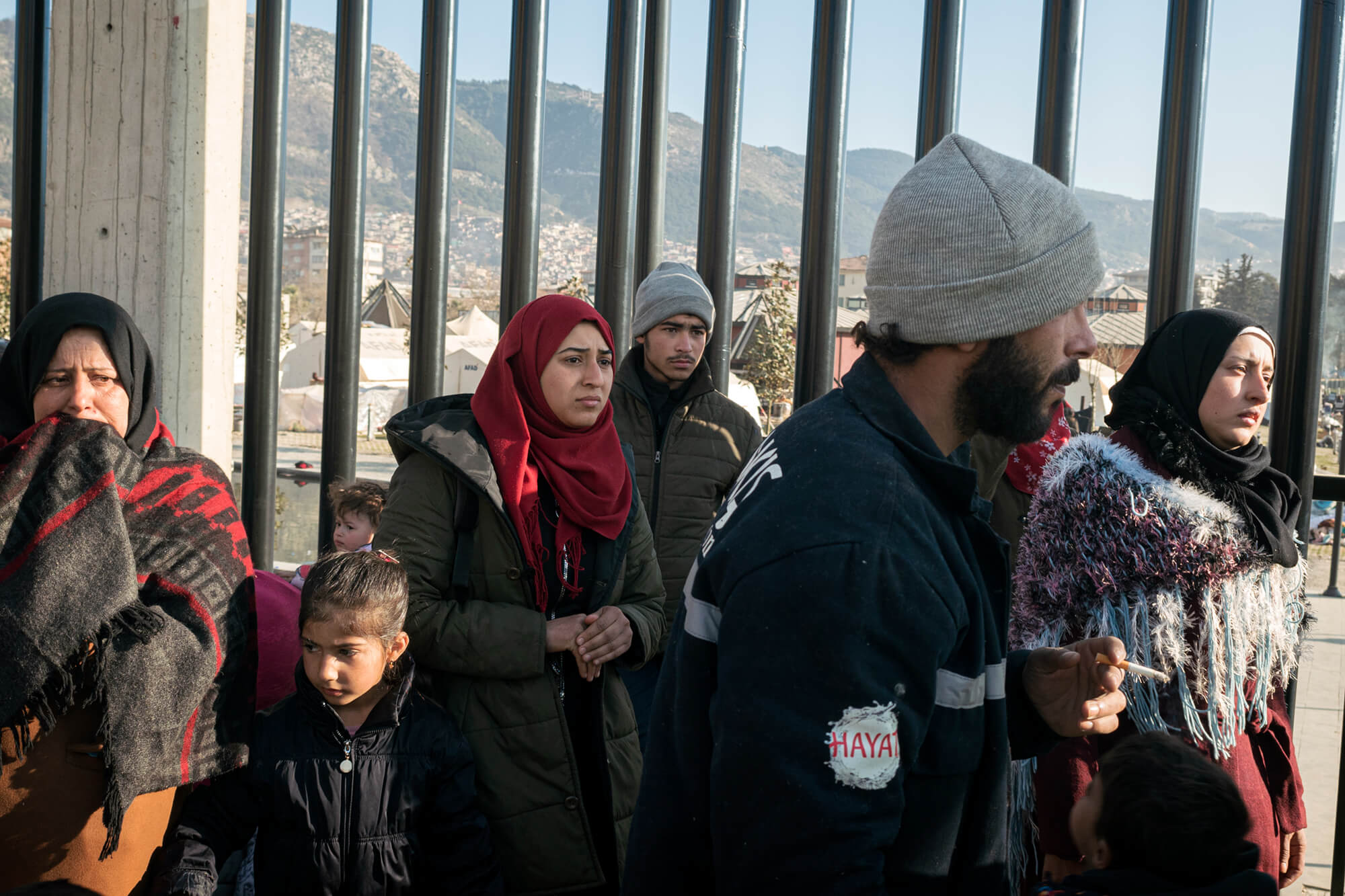 A Syrian family waits in front of a camp for displaced people in Hatay, Türkiye.