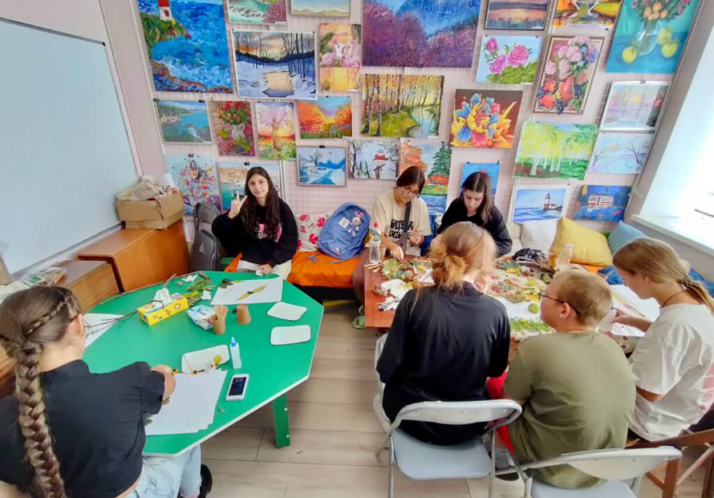 Olena and her peers use natural materials gathered outside to create art on the theme “colors of autumn” during a psychosocial support session.