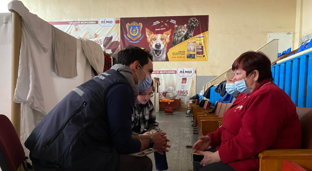 Dr. John Roberts (left) meets with a woman in Ukraine after the Russian invasion in 2022.