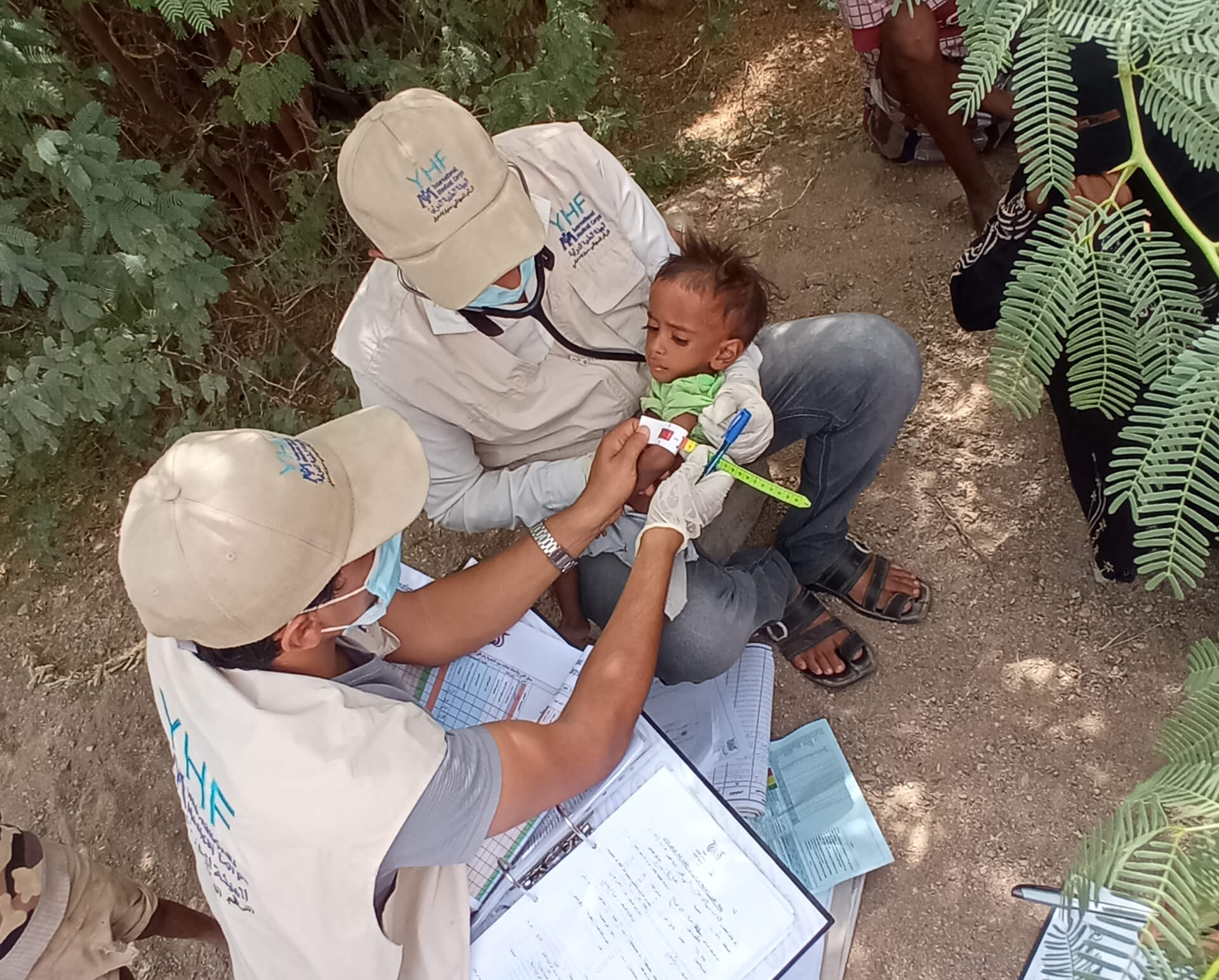 YEM_MT_healthcare_DarAlShogaVillage A mobile team member measures a child for malnutrition. The red color shows on the tape when the arm size is too thin for a healthy child.