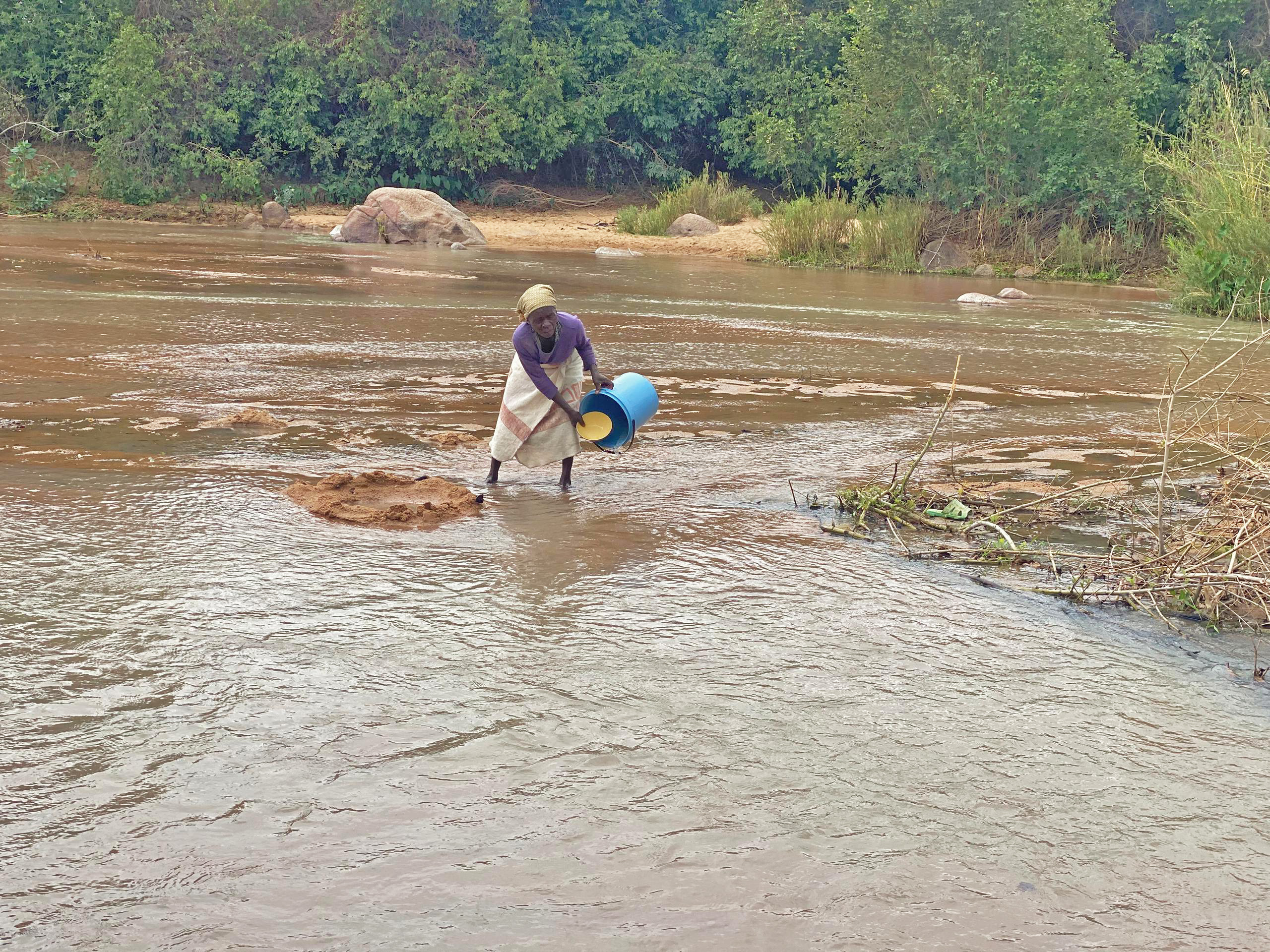 Mollen Kusereka collects water from Dewure River, relying on a makeshift filtering method to make it safer for her family's consumption.